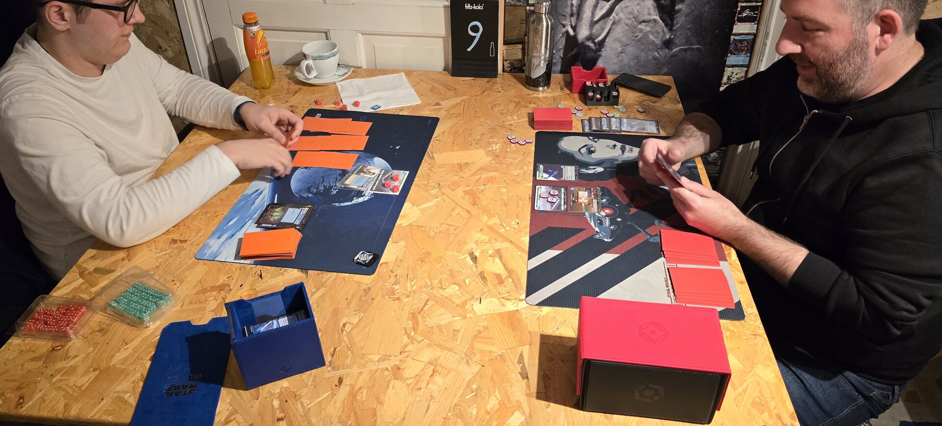 Two players enjoying a card game at a wooden table in Board & Brewed